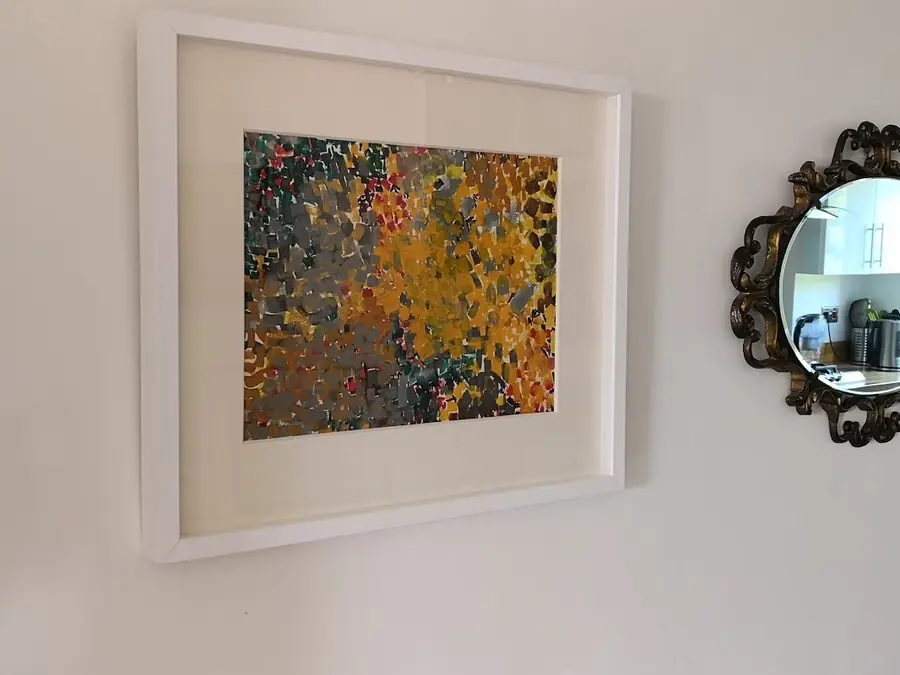 Wall display of a framed autumnal print beside an ornate black scalloped mirror